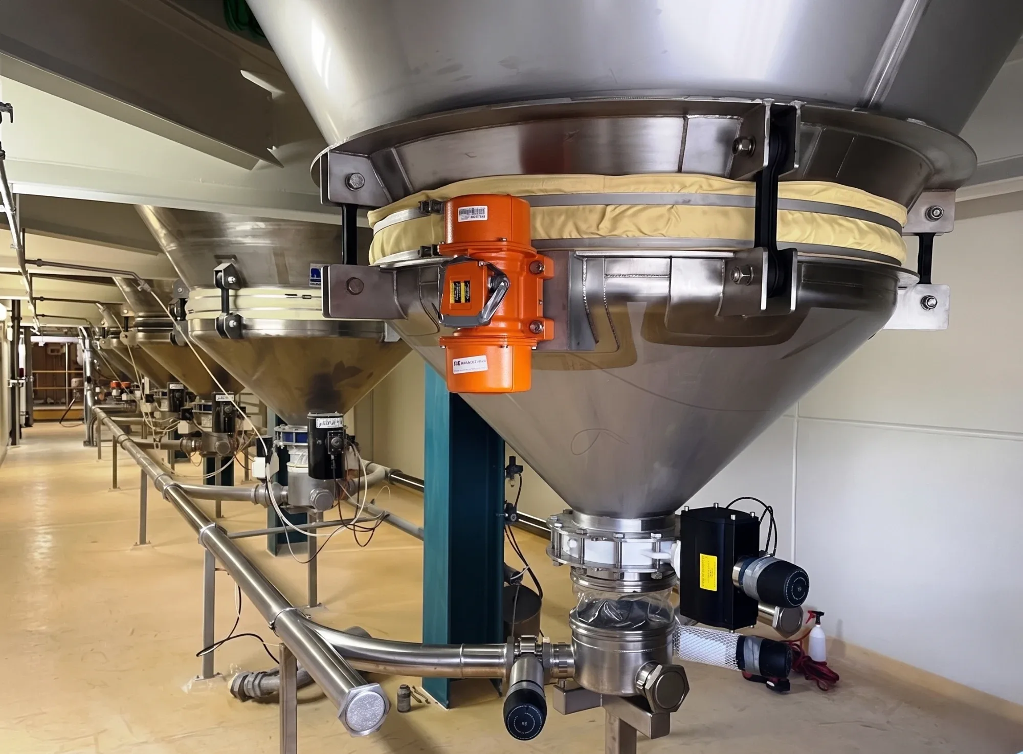 A row of TLG receival hoppers with vibrators, discharging into one conveying line